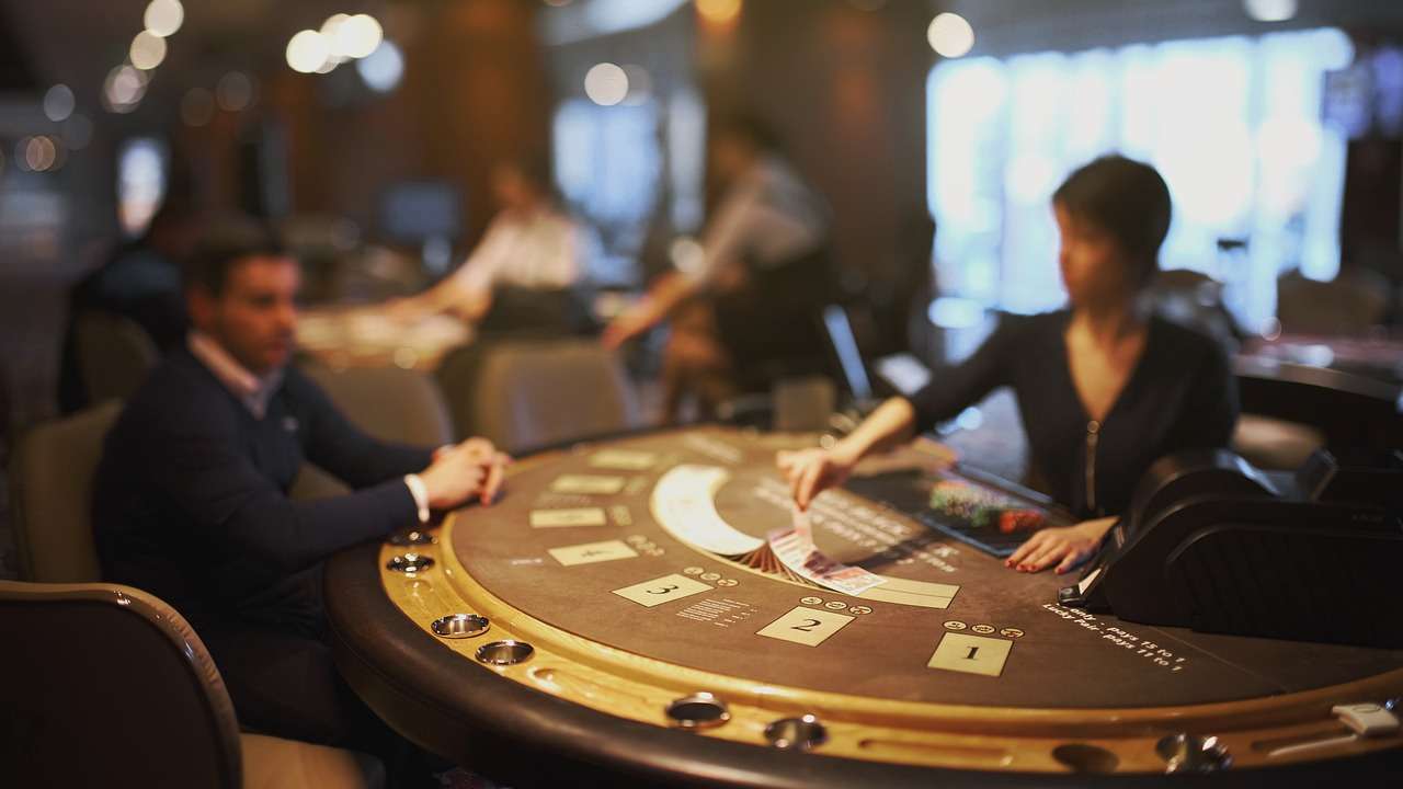 A casino dealer deals cards on a blackjack table while players observe the game.