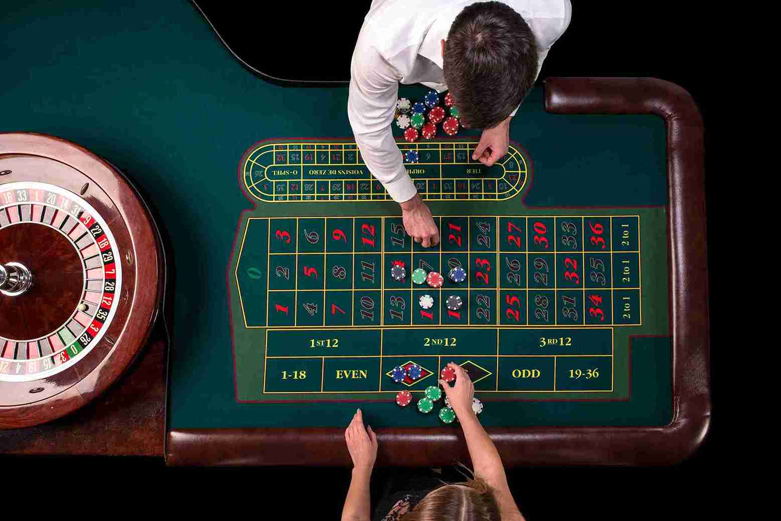Overhead view of players placing chips on a roulette table layout.